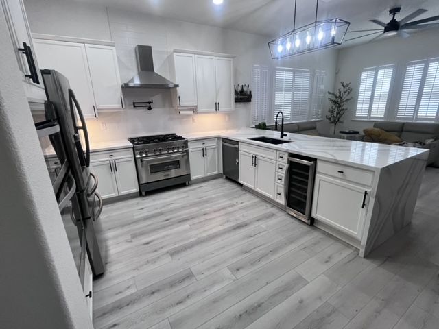 A kitchen with white cabinets , stainless steel appliances and a large island.