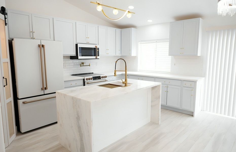 A kitchen with white cabinets , stainless steel appliances , and a large island.