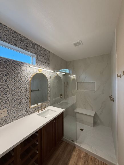 A bathroom with a walk in shower , sink and mirror.