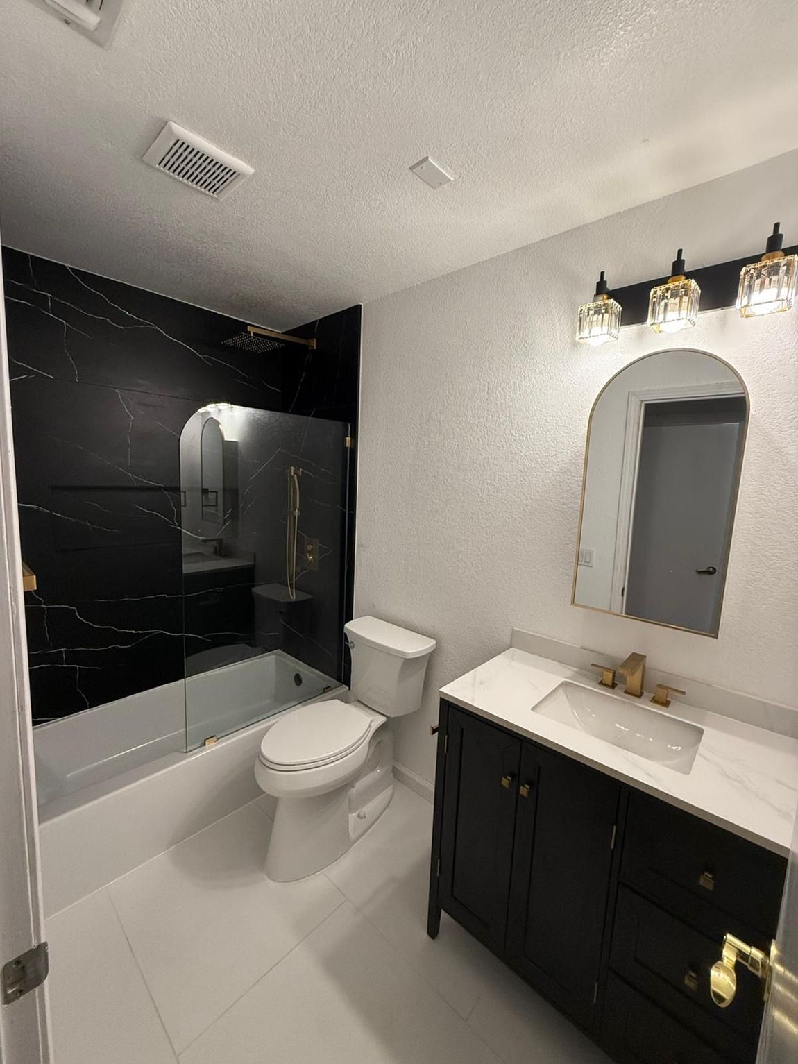 A bathroom with a toilet , sink , bathtub and mirror.