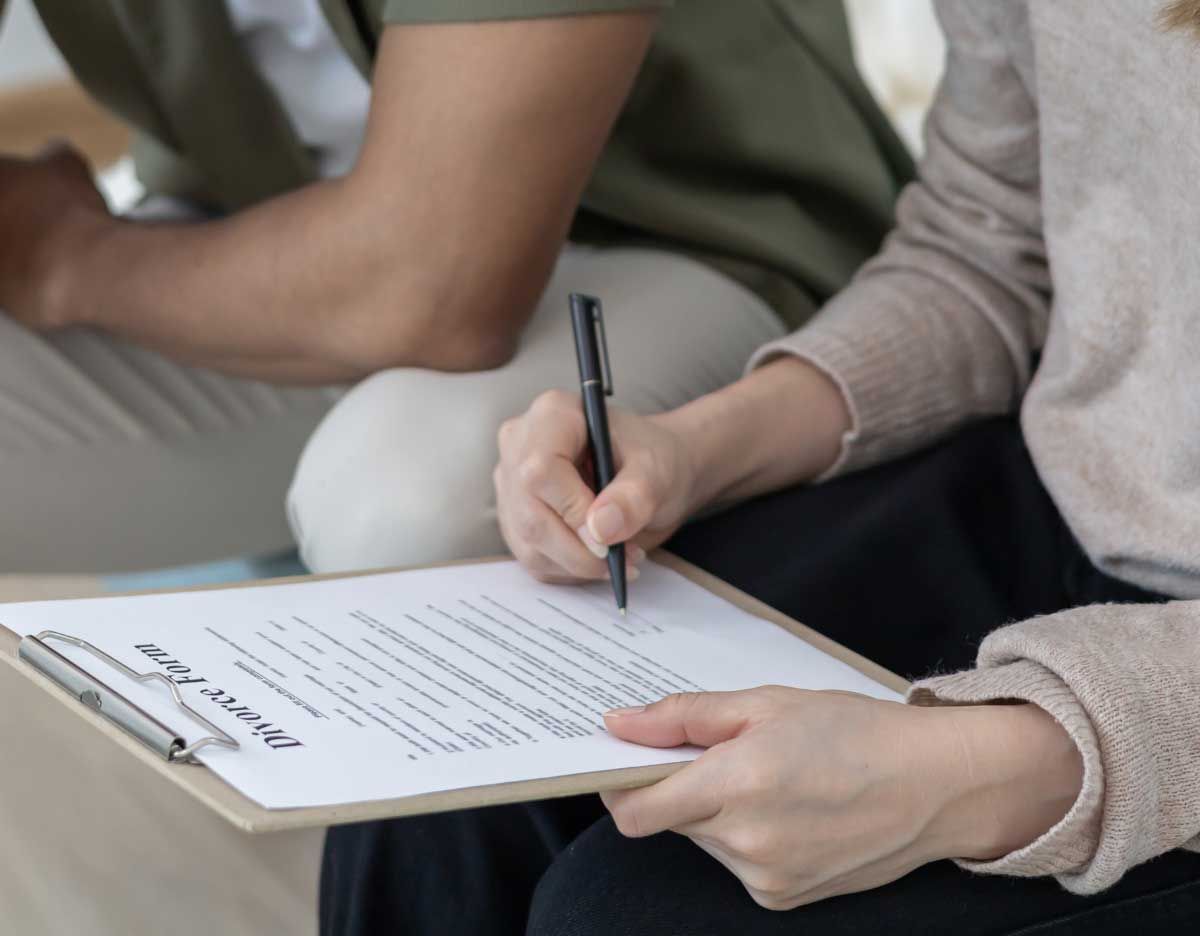Person writing on a clipboard while seated beside another person in a casual setting