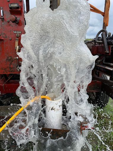 A hose is being used to pump water from a well.