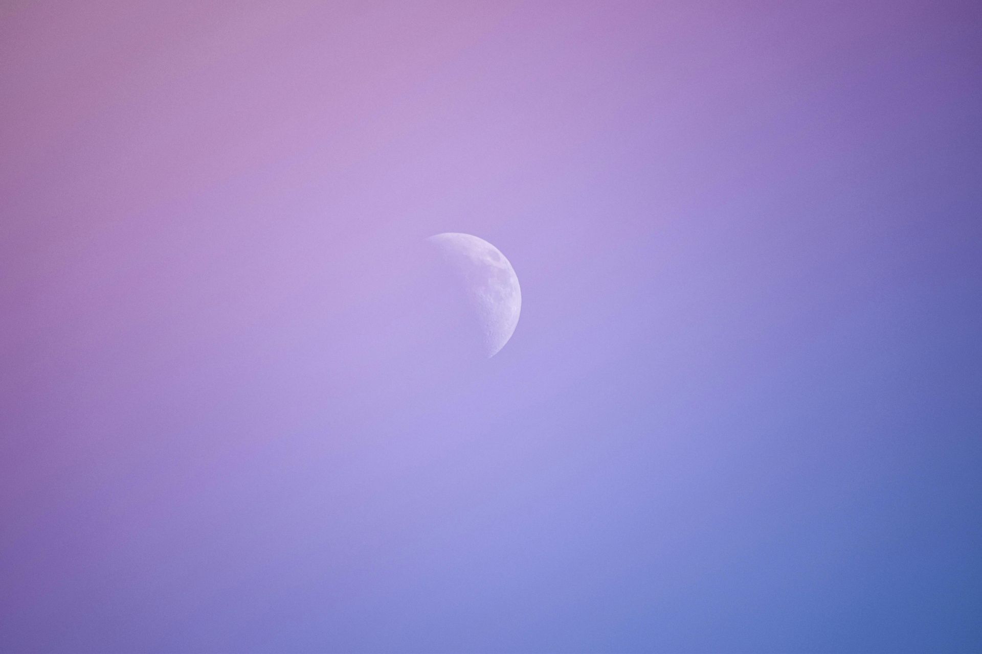 Croissant de lune dans un ciel aux dégradés de violet et de bleu.