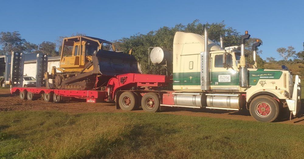 A Semi Truck is Carrying a Bulldozer on a Trailer — Oakleigh Earthmoving in Chinchilla, QLD