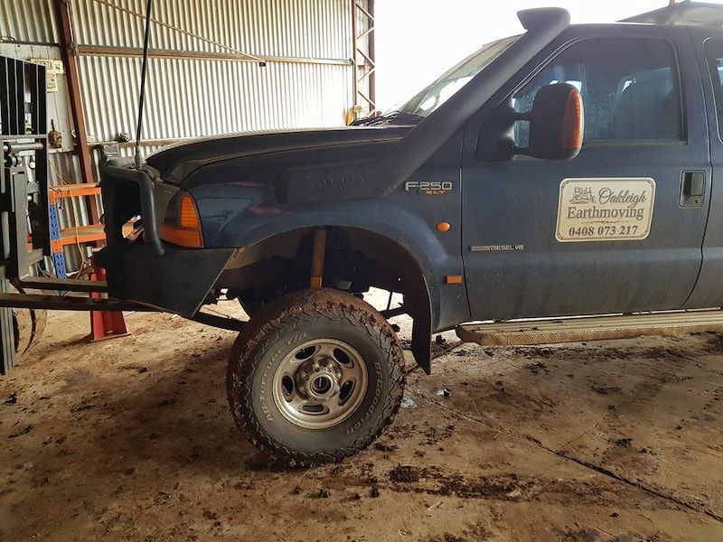A Black Truck is Parked in a Shed With a Sign on the Door — Oakleigh Earthmoving in Cotswold Hills, QLD