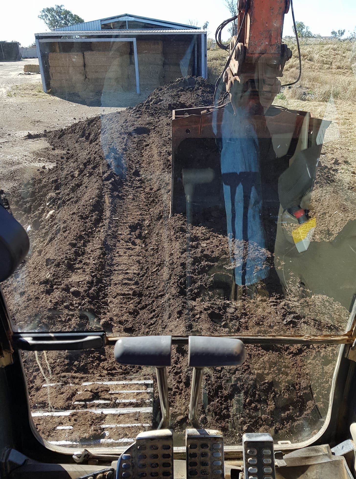 Excavator Digging a Trench Beside a Small Building, Viewed Through the Cab Window — Oakleigh Earthmoving in Cooyar, QLD