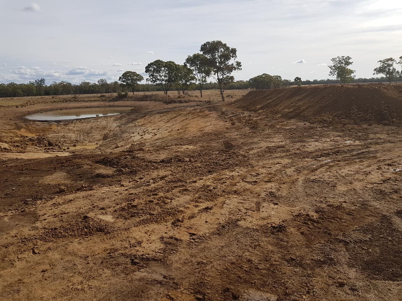 A Muddy, Barren Landscape With a Small Pond — Oakleigh Earthmoving in Chinchilla, QLD