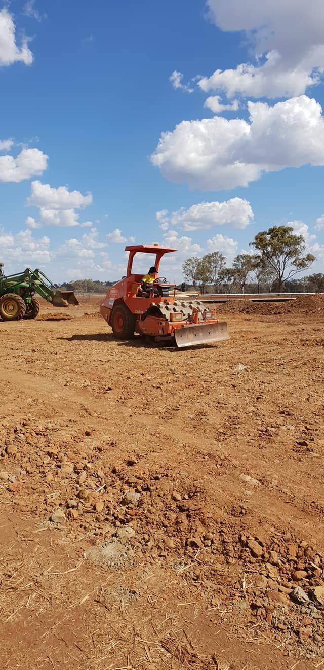 Orange Bulldozer Grading a Dirt Field Under a Blue Sky With Clouds — Oakleigh Earthmoving in Kingaroy, QLD