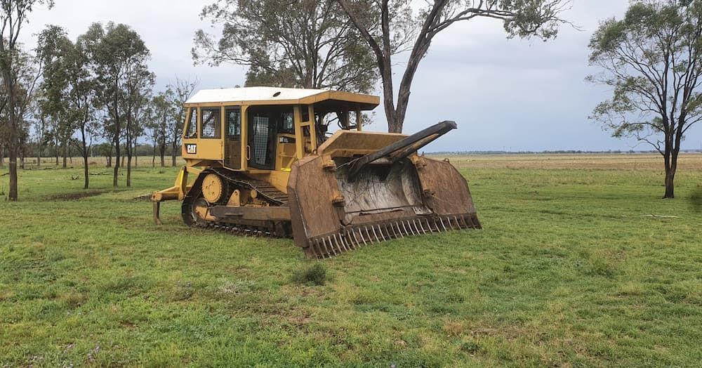 A Bulldozer is Sitting in the Middle of a Grassy Field — Oakleigh Earthmoving in Cotswold Hills, QLD