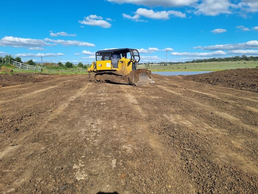 A Bulldozer is Driving Through a Dirt Field — Oakleigh Earthmoving in Cotswold Hills, QLD