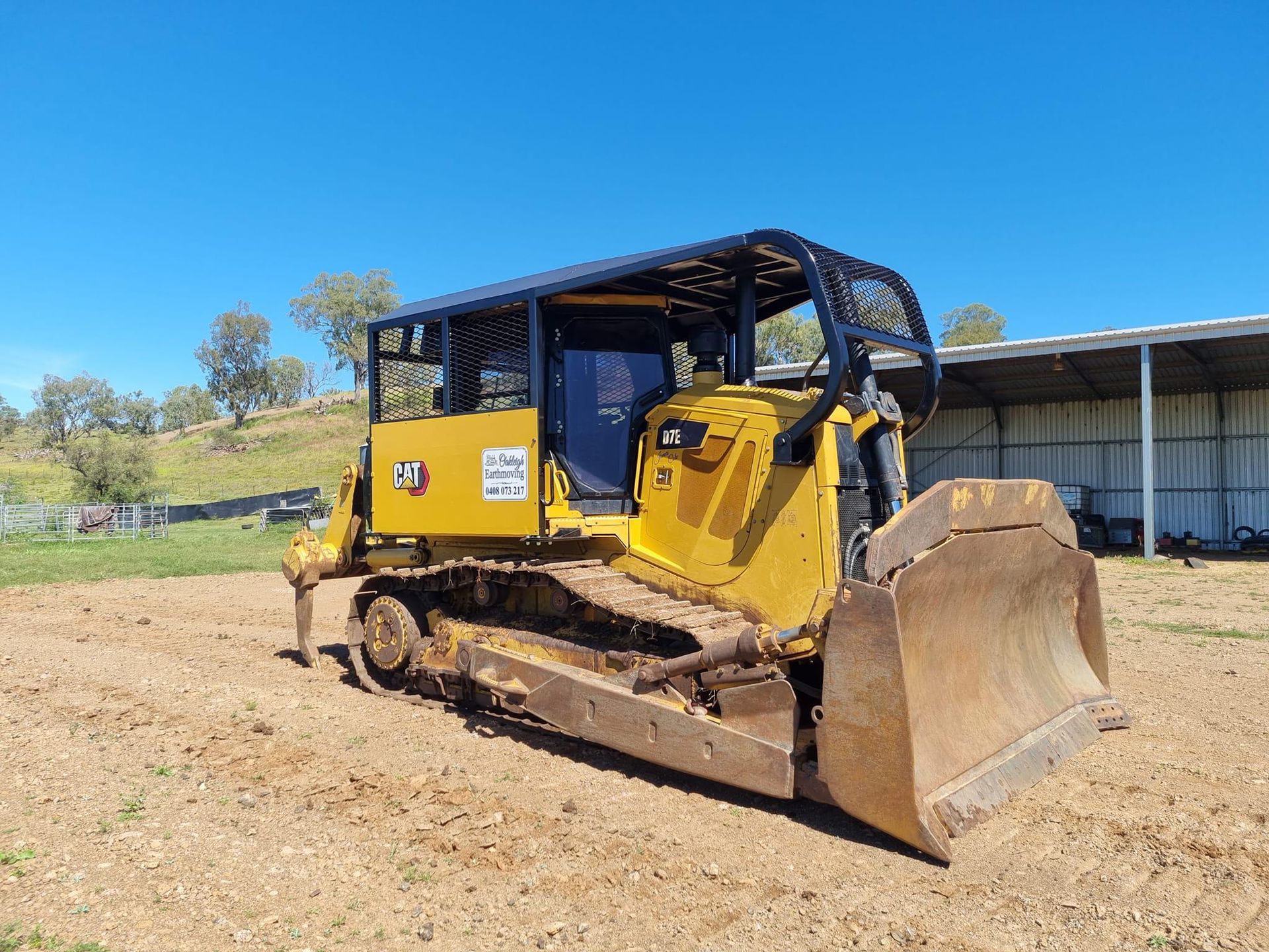 Yellow Bulldozer on Dirt Near a Shed Under a Blue Sky — Oakleigh Earthmoving in Cotswold Hills, QLD