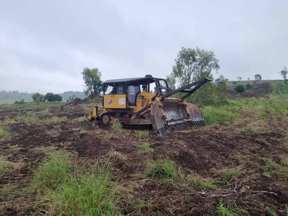 Yellow Bulldozer Clearing Muddy Field Under Cloudy Sky — Oakleigh Earthmoving in Kingaroy, QLD