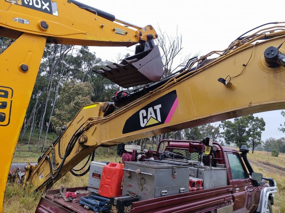 A Cat Excavator is Attached to the Back of a Truck — Oakleigh Earthmoving in Cotswold Hills, QLD