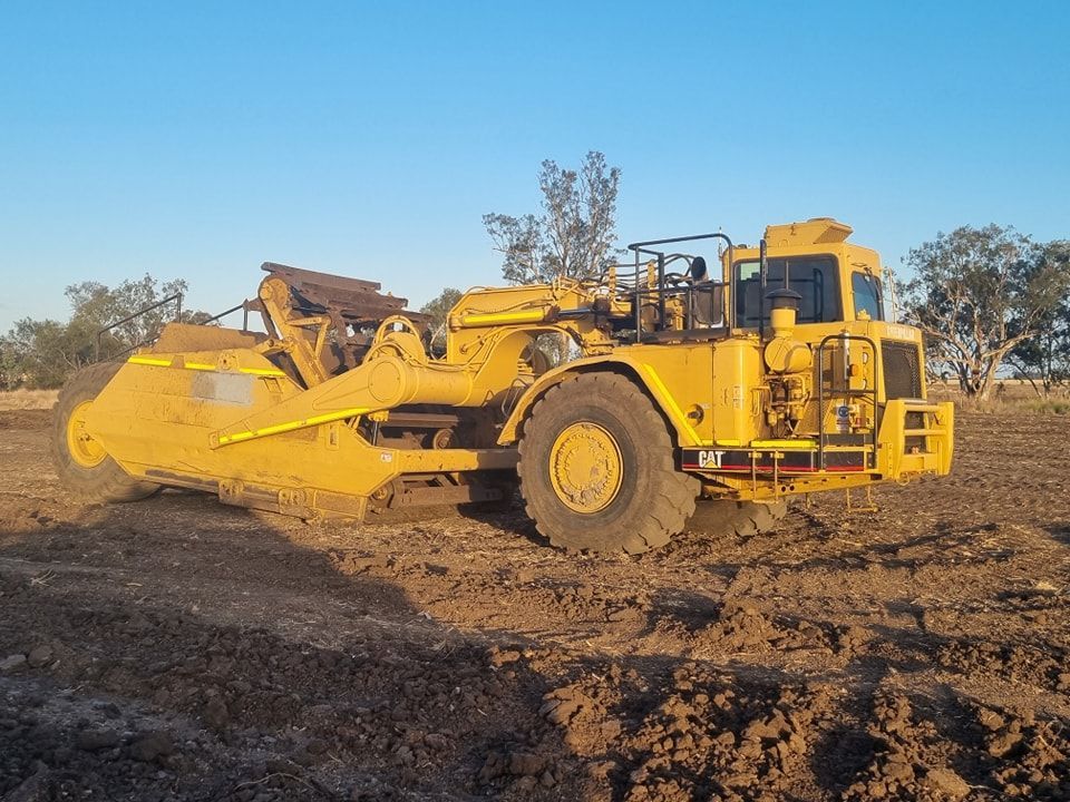Yellow Construction Grader on a Dirt Site Under a Clear Blue Sky — Oakleigh Earthmoving in Toowoomba, QLD