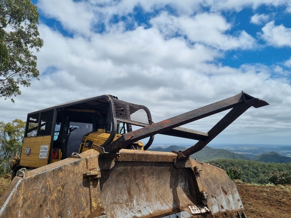 Yellow Bulldozer With Raised Blade Clearing Earth at a Rural Construction Site — Oakleigh Earthmoving in Kingaroy, QLD