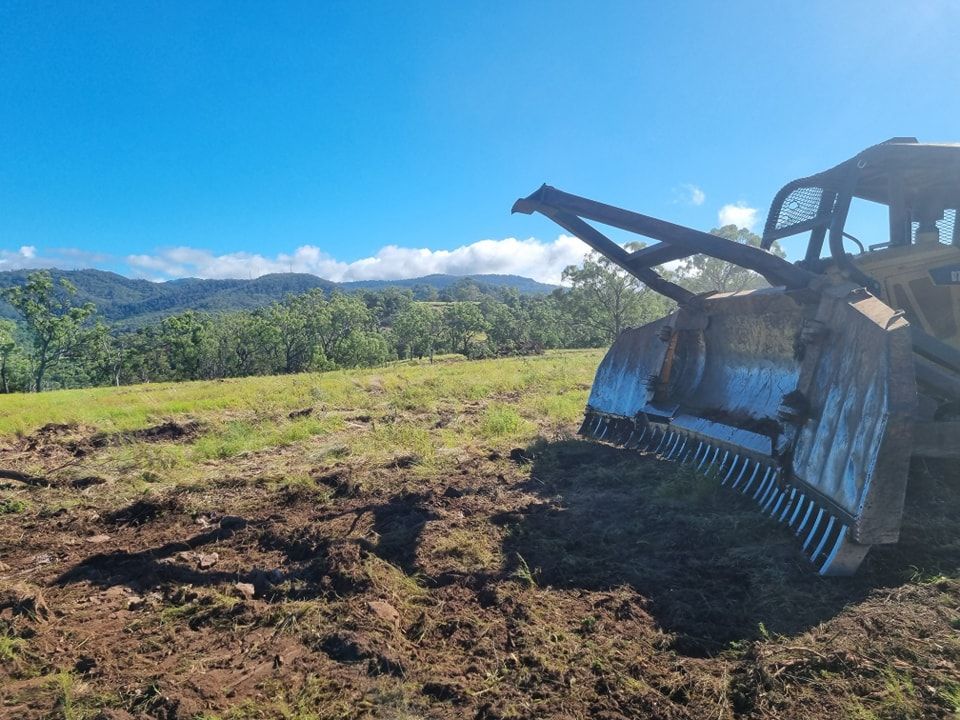 Bulldozer on a Muddy Hillside With Mountains and Blue Sky in the Background — Oakleigh Earthmoving in Chinchilla, QLD