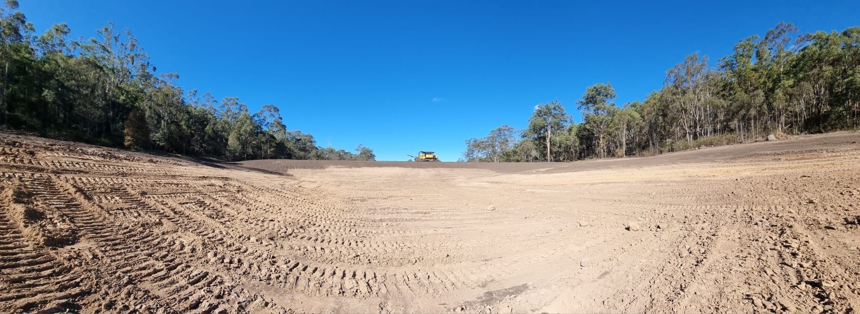 Wide Sandy Dirt Road Through Dry Scrub Under a Bright Blue Sky — Oakleigh Earthmoving in Warwick, QLD