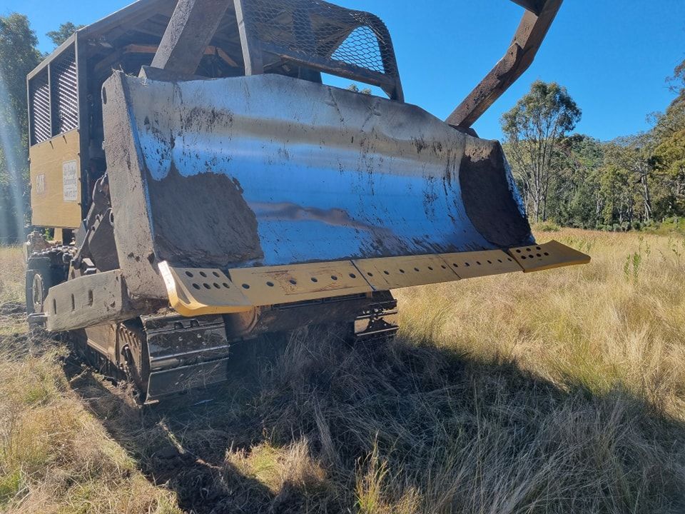 Large Tracked Bulldozer With Raised Blade on a Grassy Dirt Field Under a Blue Sky — Oakleigh Earthmoving in Warwick, QLD