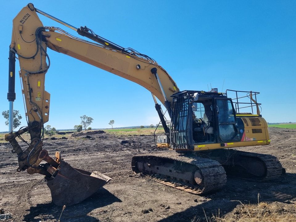 Yellow Excavator Working on a Dirt Site Under a Clear Blue Sky — Oakleigh Earthmoving in Goondiwindi, QLD