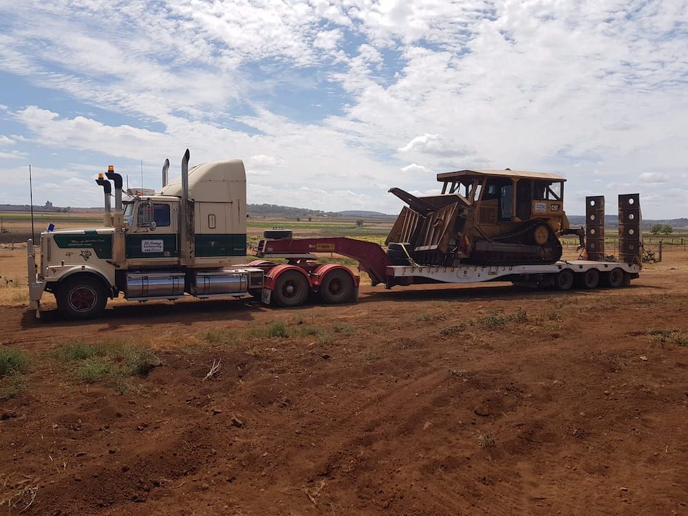 A Semi Truck is Carrying a Bulldozer on a Trailer — Oakleigh Earthmoving in Kingaroy, QLD