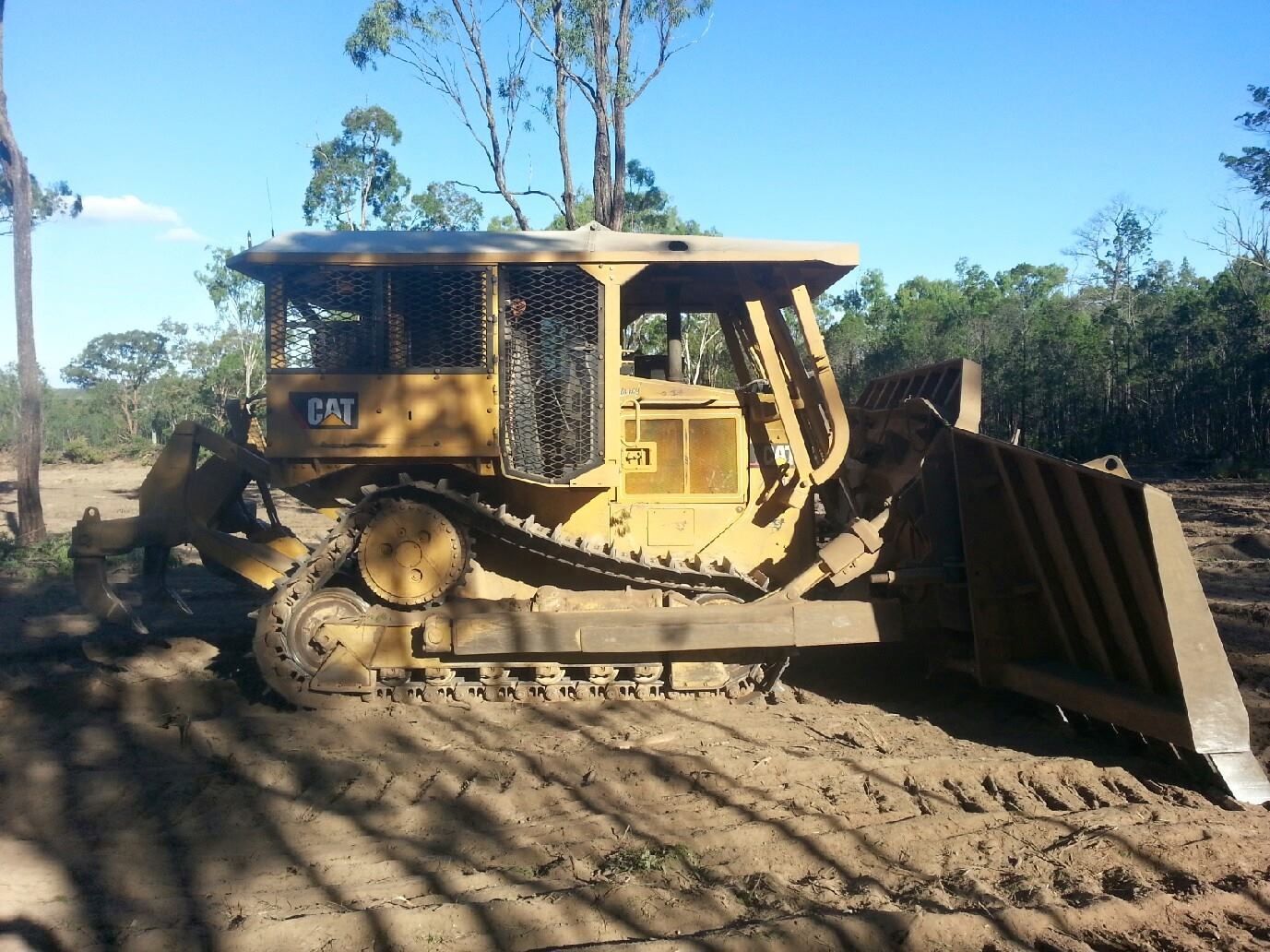 Yellow Bulldozer Pushing Dirt on a Muddy Site Under a Blue Sky — Oakleigh Earthmoving in Warwick, QLD