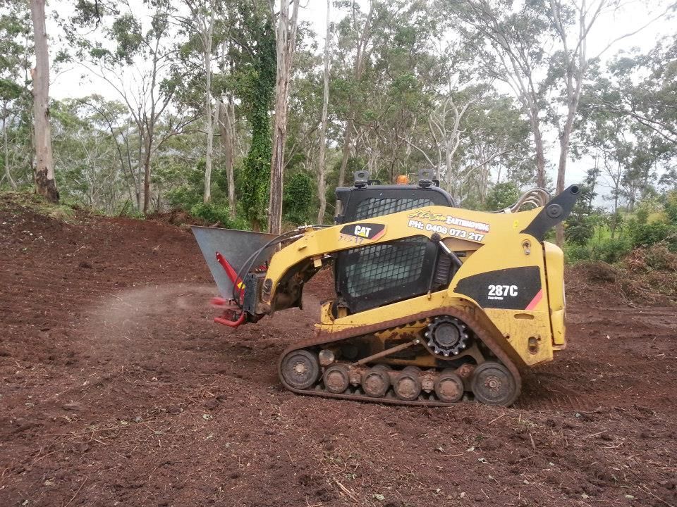 Yellow Compact Tracked Loader Clearing Dirt on a Wooded Hillside — Oakleigh Earthmoving in Goondiwindi, QLD