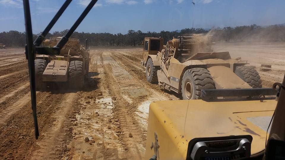 Construction Vehicles Grading a Muddy Dirt Road on a Sunny Worksite — Oakleigh Earthmoving in Chinchilla, QLD