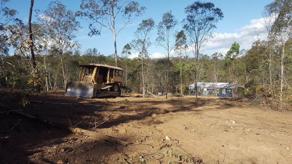 Yellow Bulldozer Clearing a Dirt Lot in a Wooded Area — Oakleigh Earthmoving in Kingaroy, QLD