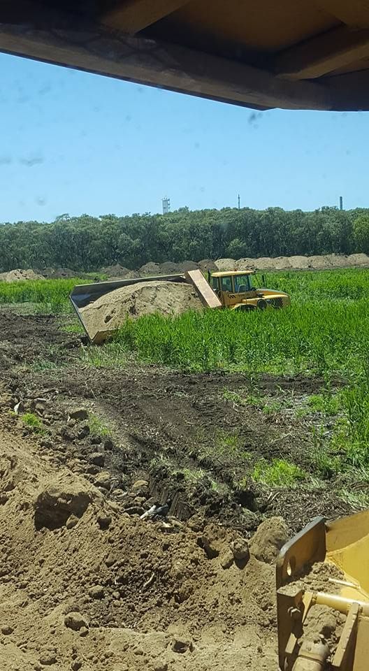 Cleared Muddy Field With a Small Excavator and a Concrete Block Under a Cloudy Sky — Oakleigh Earthmoving in Chinchilla, QLD