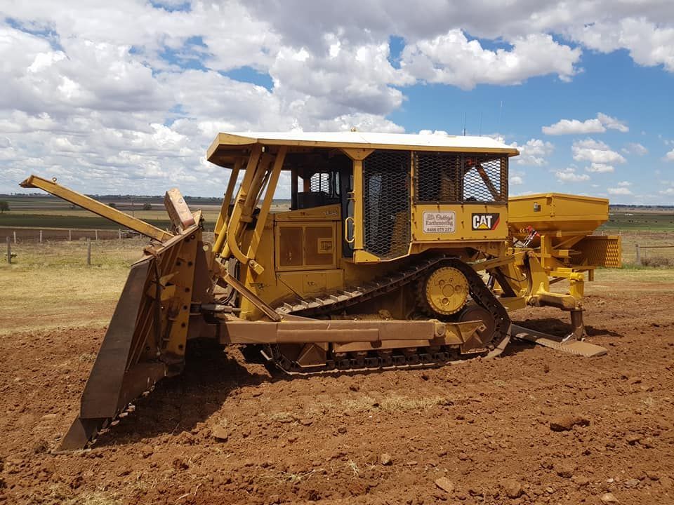 Yellow Bulldozer Clearing Dirt on a Dry Construction Site Under a Cloudy Sky — Oakleigh Earthmoving in Toowoomba, QLD