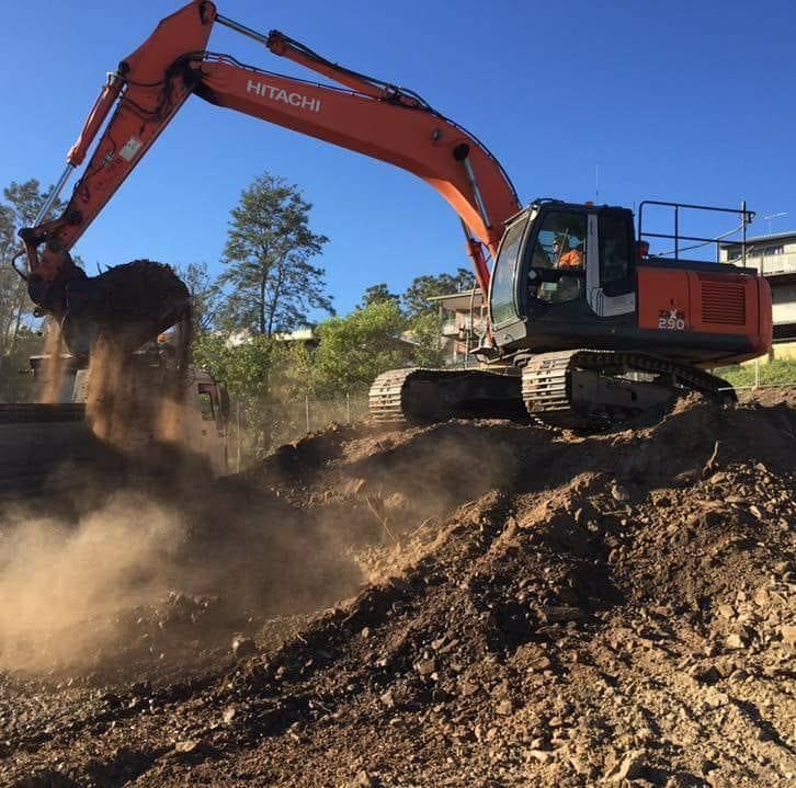 Orange Excavator Dumping Dirt on a Rocky Hillside — Oakleigh Earthmoving in Chinchilla, QLD