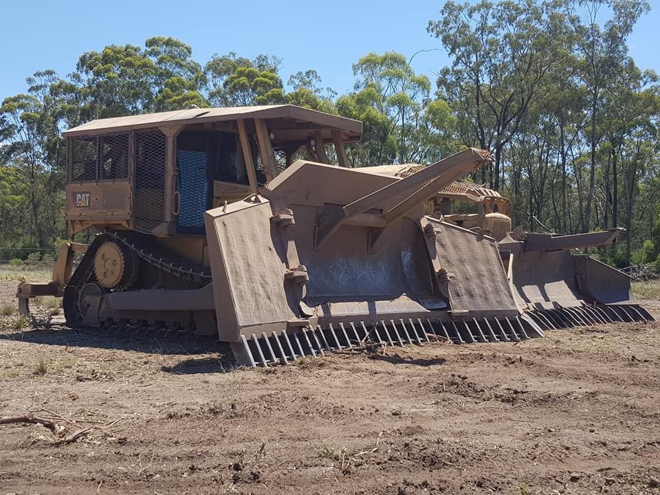 Bulldozer With Raised Front Blade and Wide Tracks Parked on a Dirt Clearing — Oakleigh Earthmoving in Chinchilla, QLD