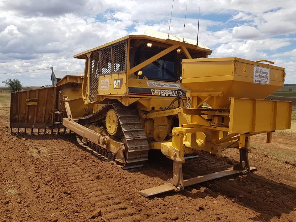 Yellow Bulldozer With Metal Tracks and Front Blade on a Dirt Road, Hauling Earth — Oakleigh Earthmoving in Toowoomba, QLD