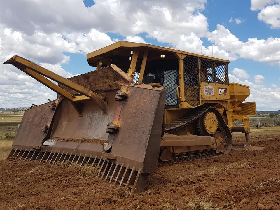 Yellow Bulldozer With a Large Front Blade Pushing Dirt on a Muddy Construction Site — Oakleigh Earthmoving in Toowoomba, QLD