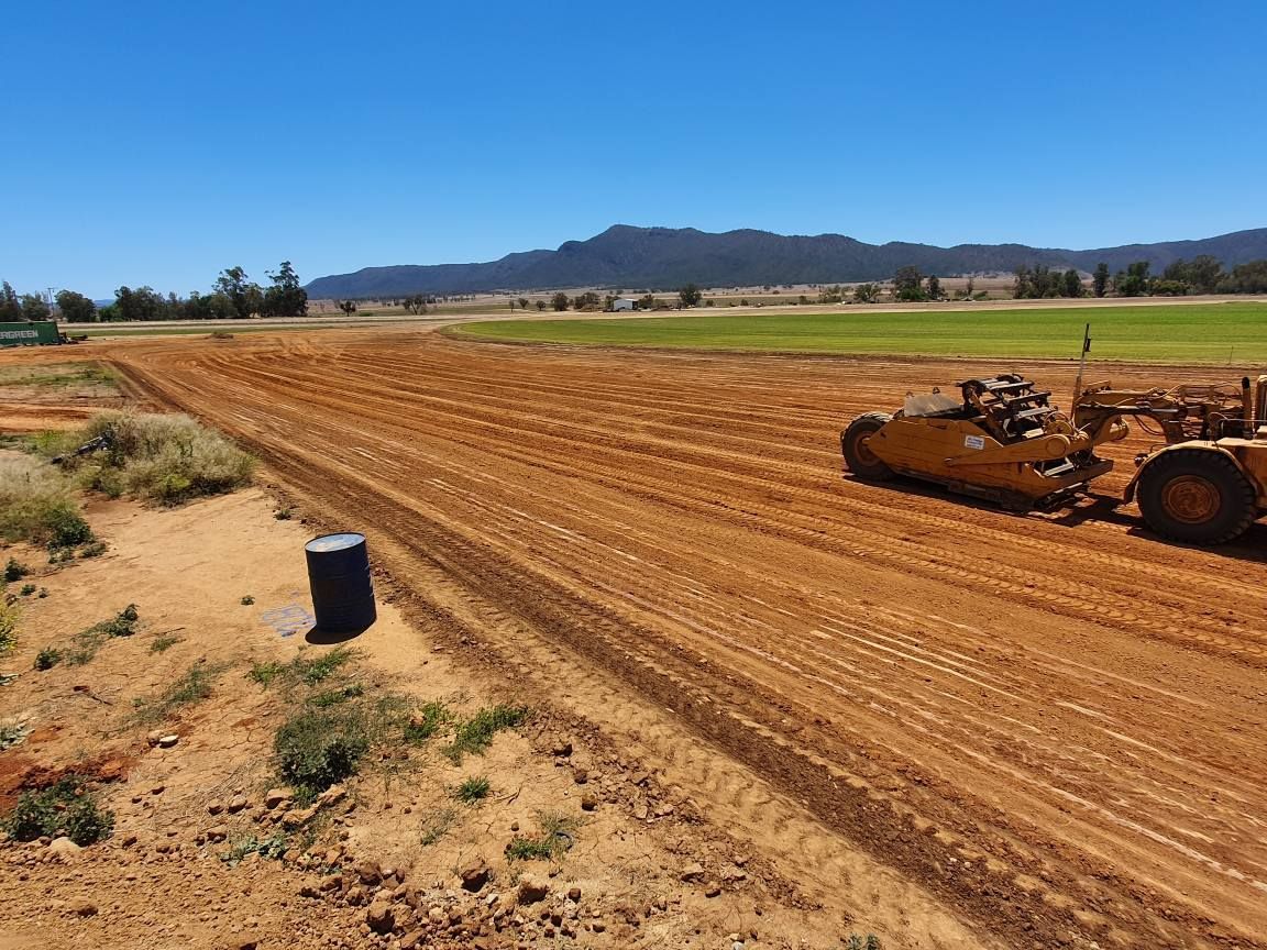 Wide Dirt Racetrack With a Bulldozer Grading the Surface Under a Clear Blue Sky — Oakleigh Earthmoving in Chinchilla, QLD