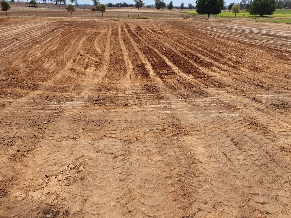 Freshly Plowed, Dry Field With Parallel Tire Tracks Under a Clear Sky — Oakleigh Earthmoving in Toowoomba, QLD