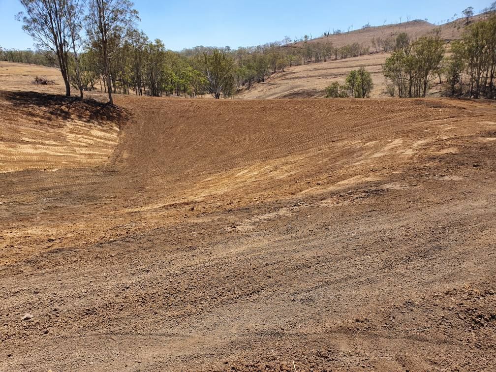 Dry Dirt Clearing on a Hillside With Sparse Trees and a Brown Hillside — Oakleigh Earthmoving in Chinchilla, QLD