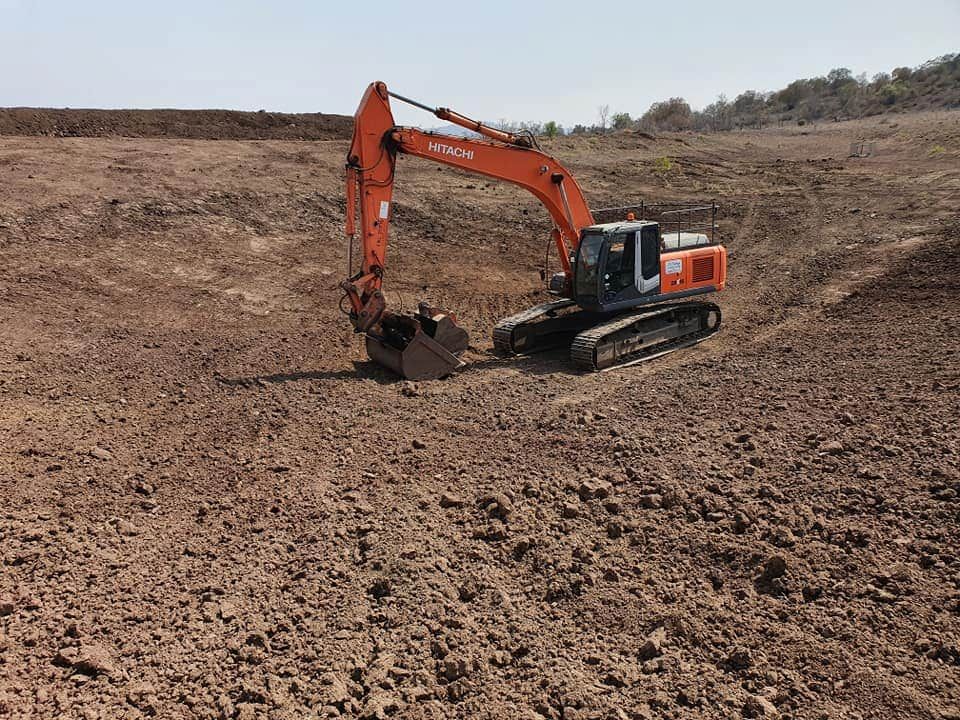 A Large Excavator is Driving Through a Dirt Field — Oakleigh Earthmoving in Dalby, QLD