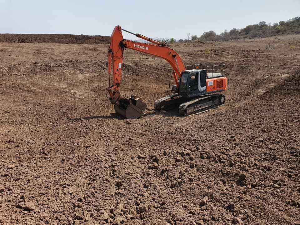 Orange Excavator Digging in a Barren Dirt Field Under a Clear Sky — Oakleigh Earthmoving in Warwick, QLD