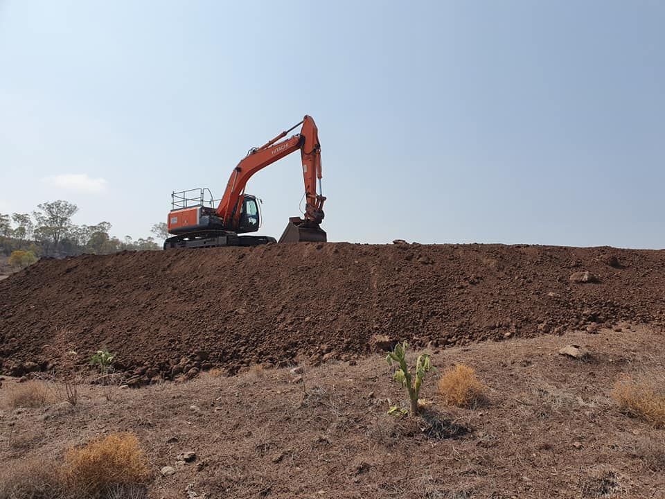 Orange Excavator on a Dirt Mound Under a Clear Sky — Oakleigh Earthmoving in Warwick, QLD