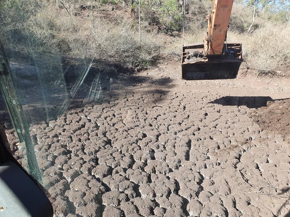 Excavator Beside a Cracked, Dry Dirt Surface in a Dusty Outdoor Worksite — Oakleigh Earthmoving in Moonie, QLD