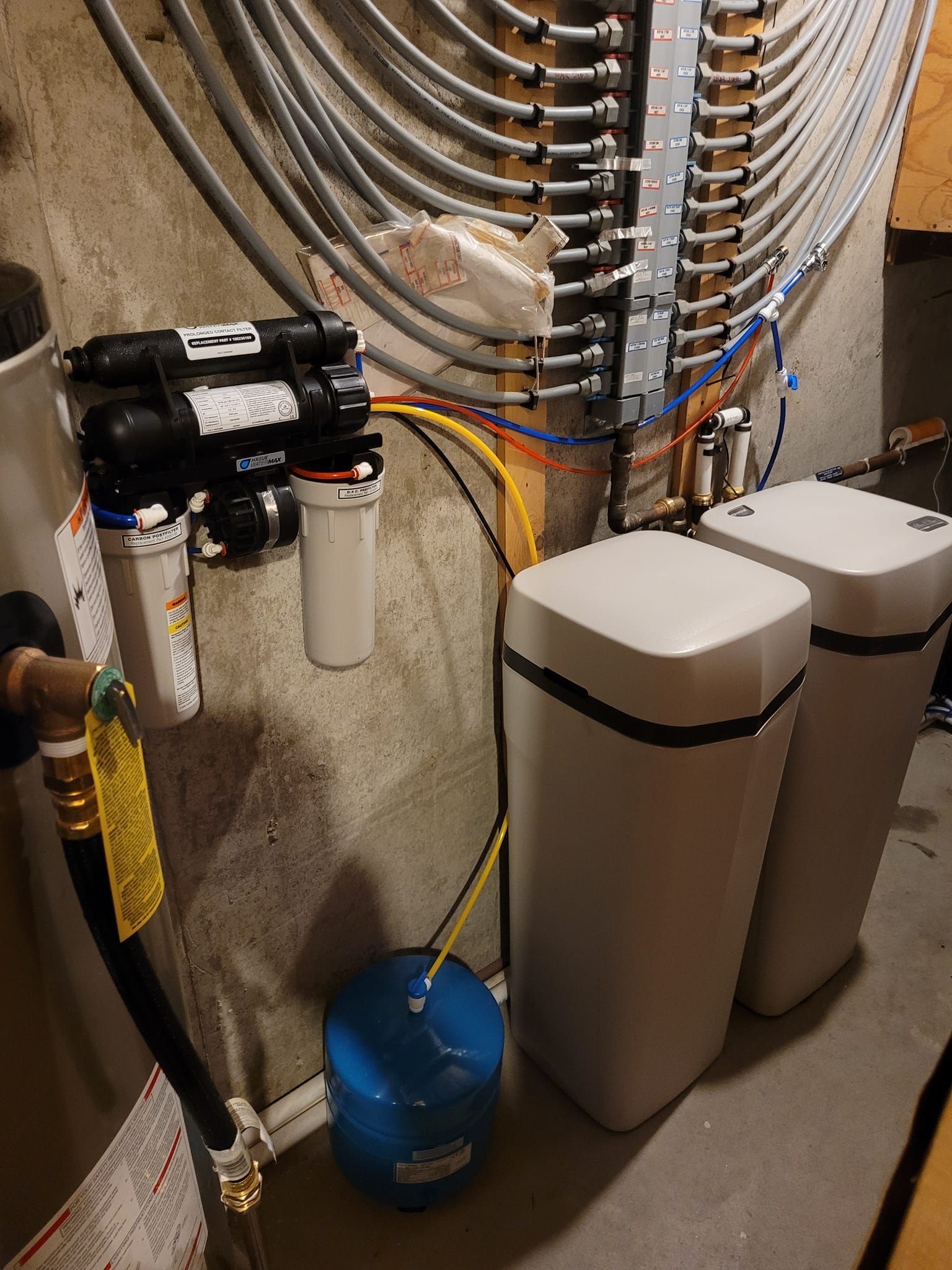 Water filtration system with tanks, pipes, and electrical wiring on a wall.