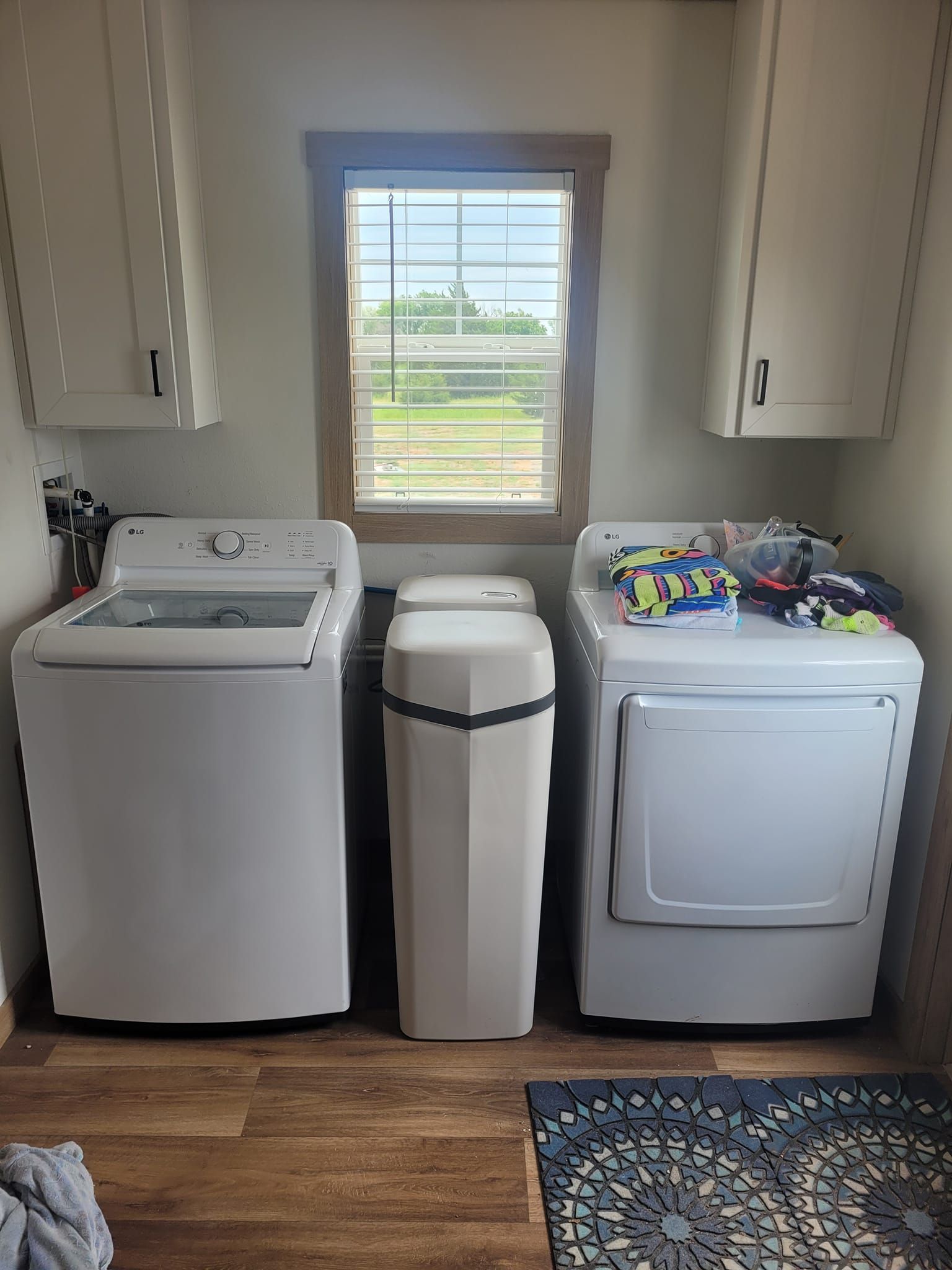 Two white water softener tanks in a utility closet, with pipes visible overhead.