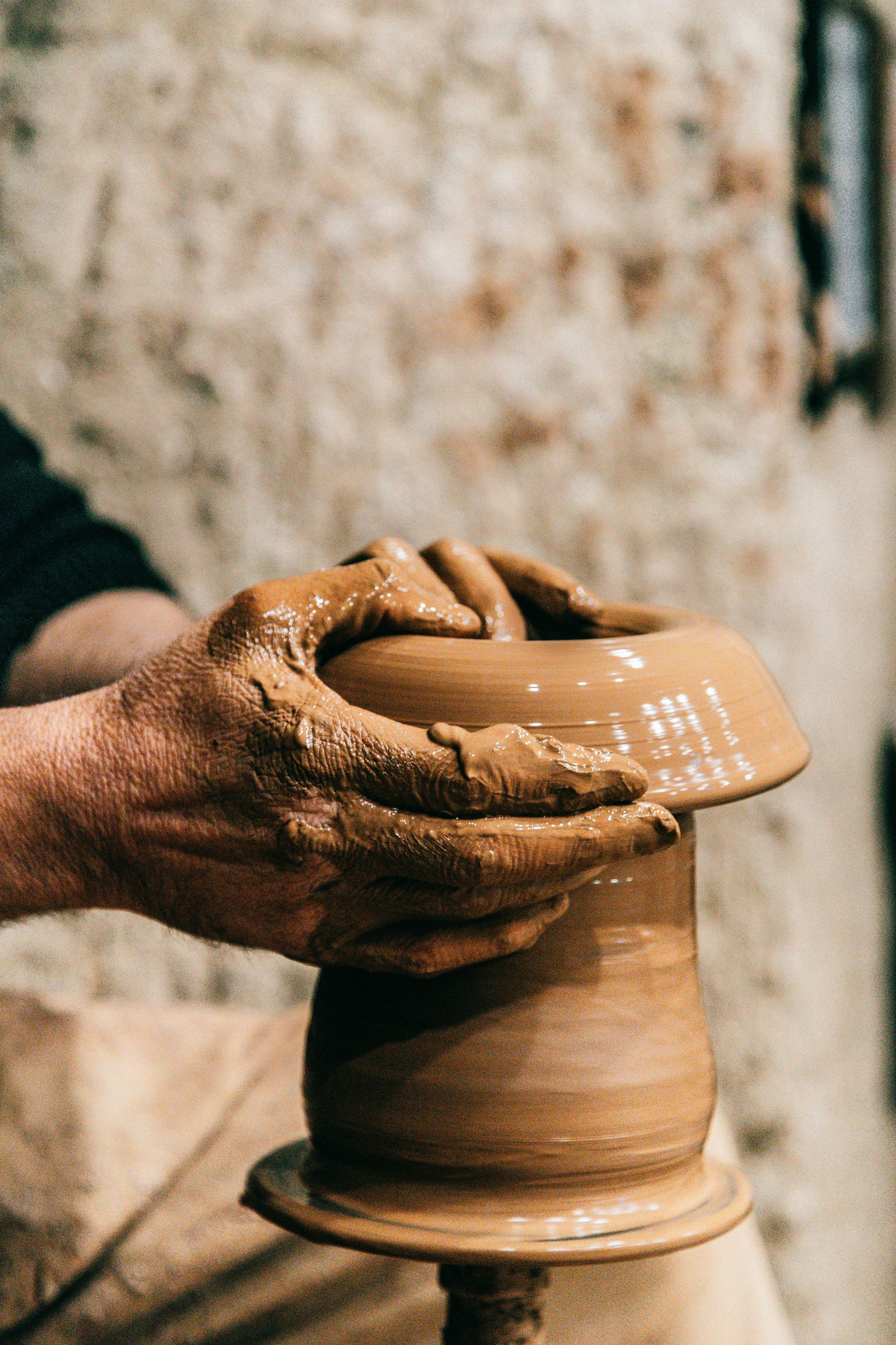 A person is making a pot on a pottery wheel.