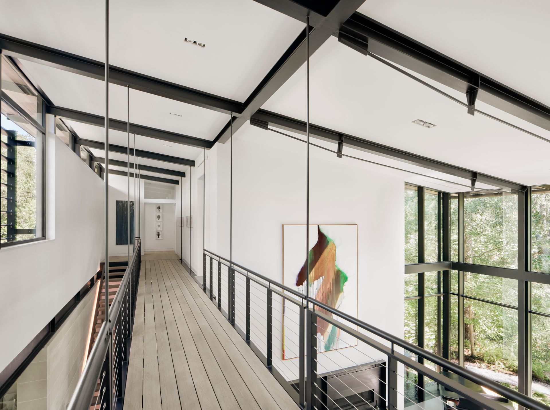 a long hallway with a railing and a painting on the wall