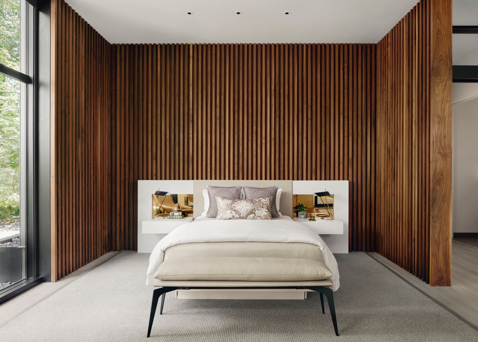 a bedroom with a bed and a bench in front of a wooden wall .