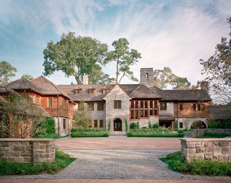 a large house with a driveway leading to it and trees in front of it .