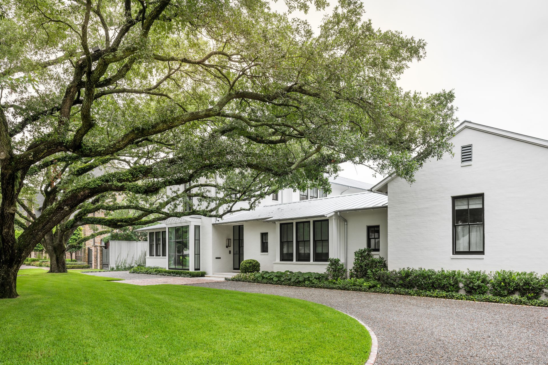 a white house with a gravel driveway and trees in front of it .