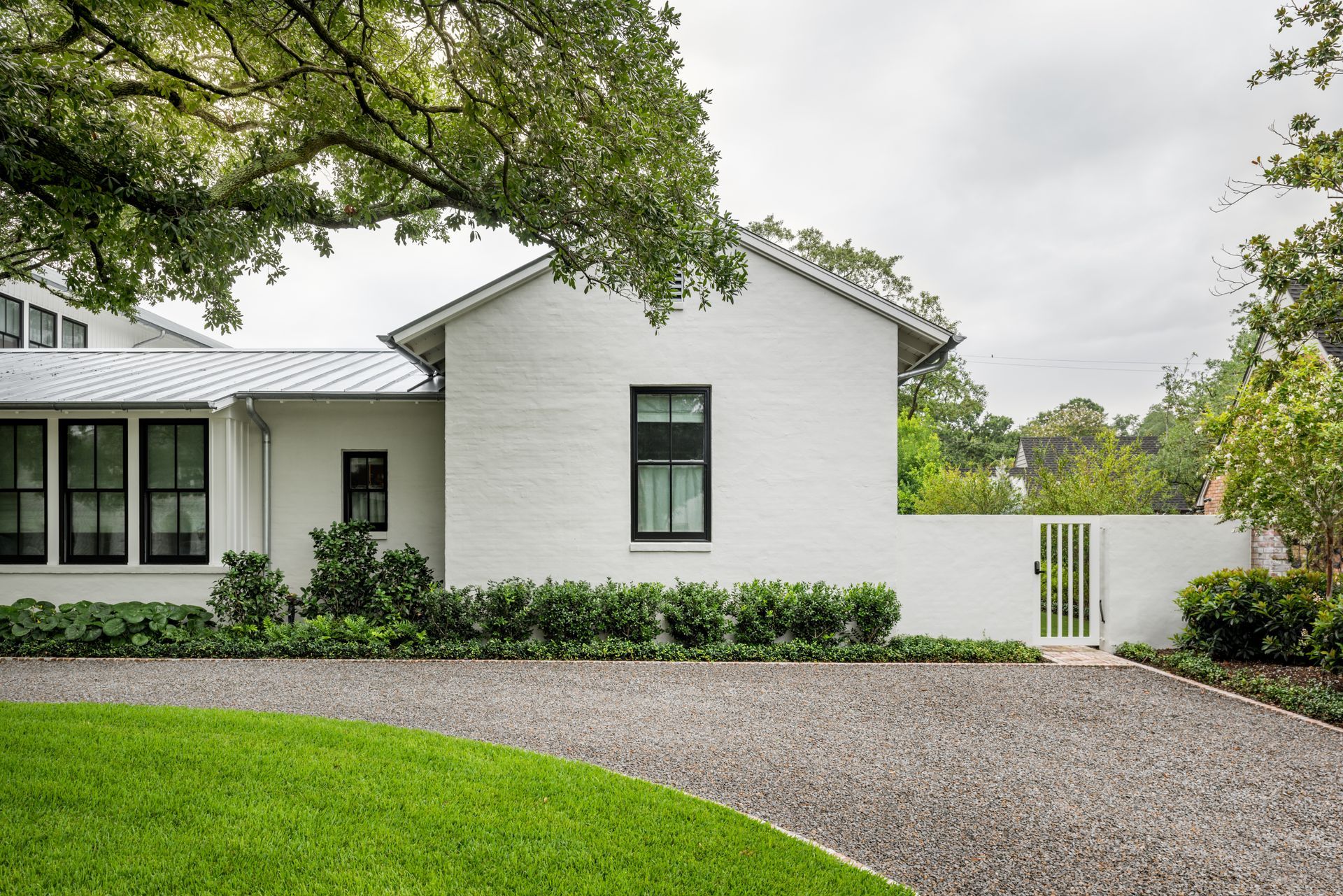 a white house with black windows and a gravel driveway .
