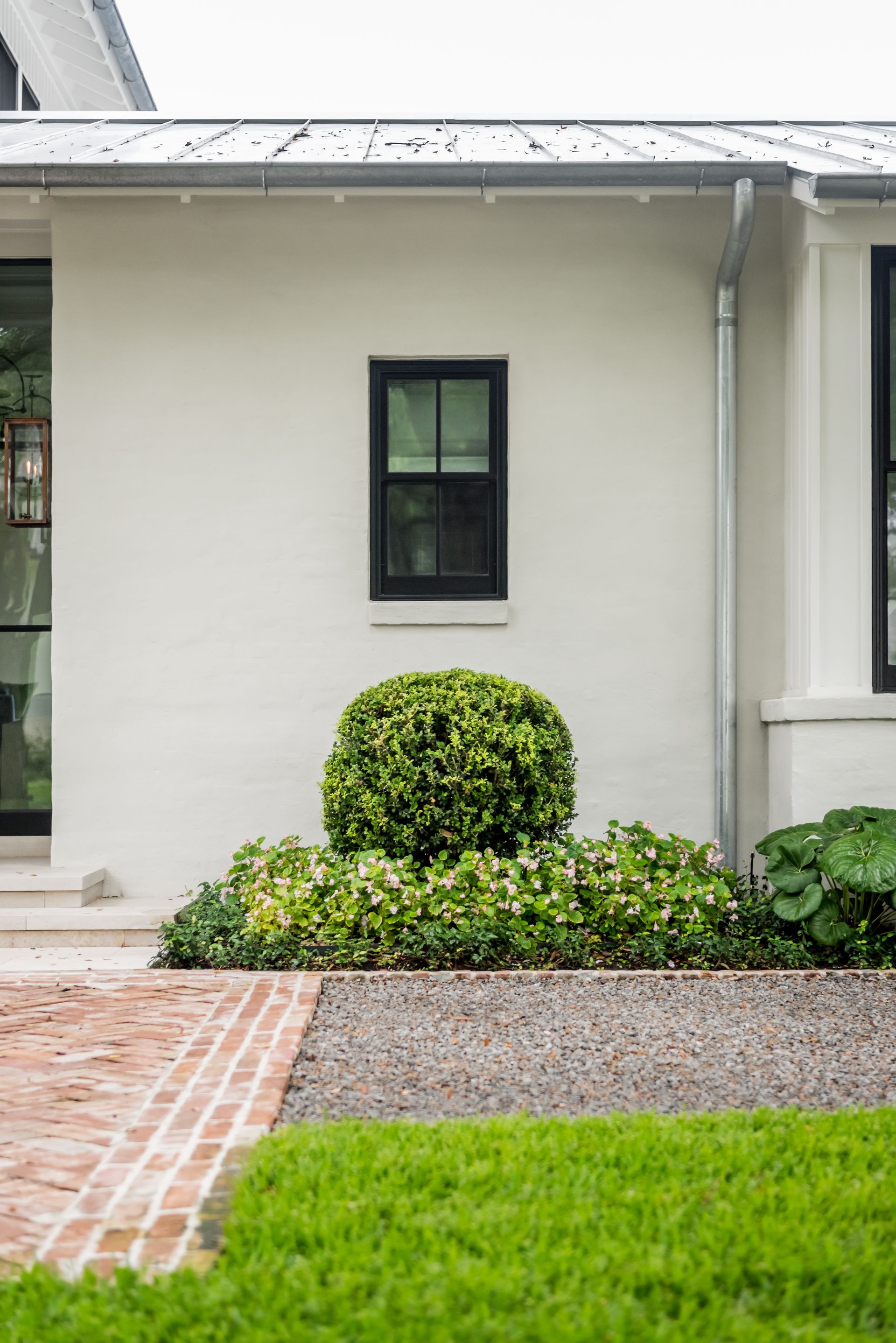 a white house with a black window and a brick walkway .